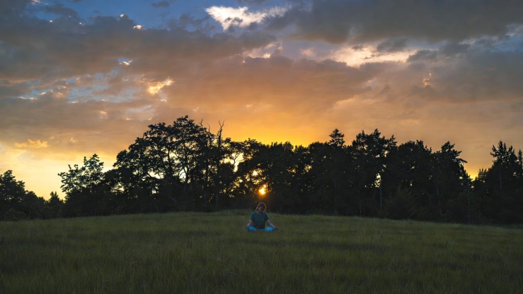 Person meditating in nature to cope with sensory triggers in PTSD for emotional stability.